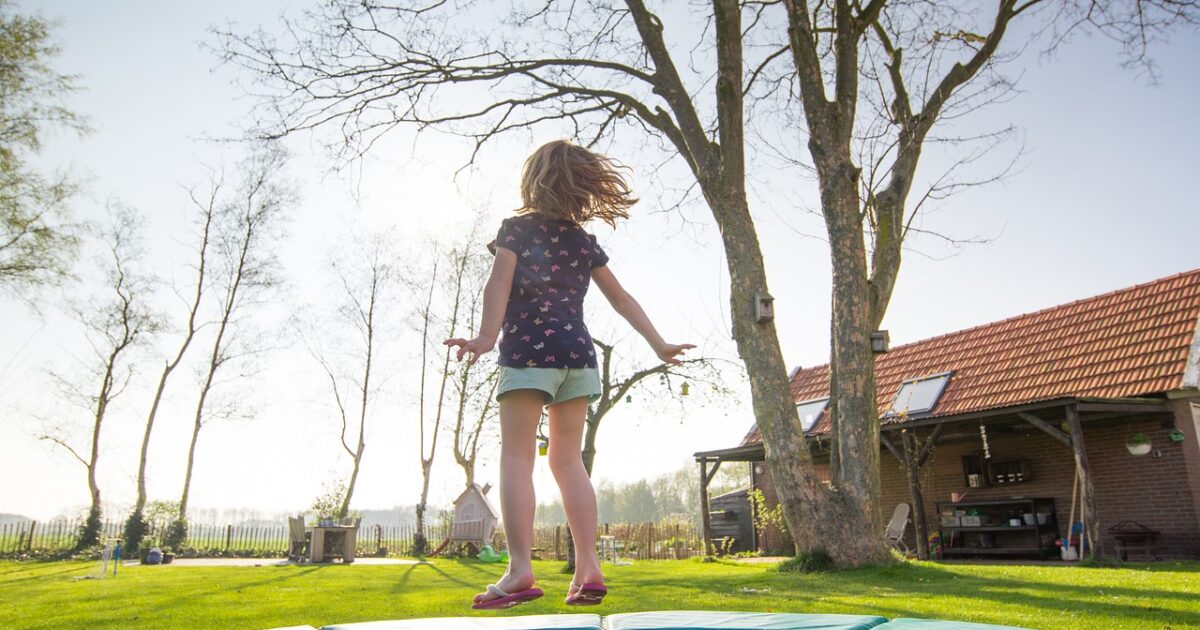 A child joyfully jumping on a trampoline, engaging in a sensory activity that promotes balance, movement, and self-regulation as part of a sensory-friendly environment.