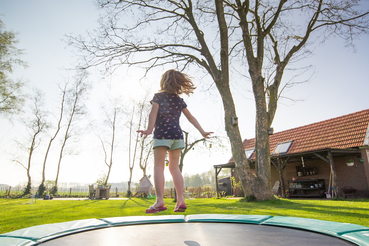 A child joyfully jumping on a trampoline, engaging in a sensory activity that promotes balance, movement, and self-regulation as part of a sensory-friendly environment.